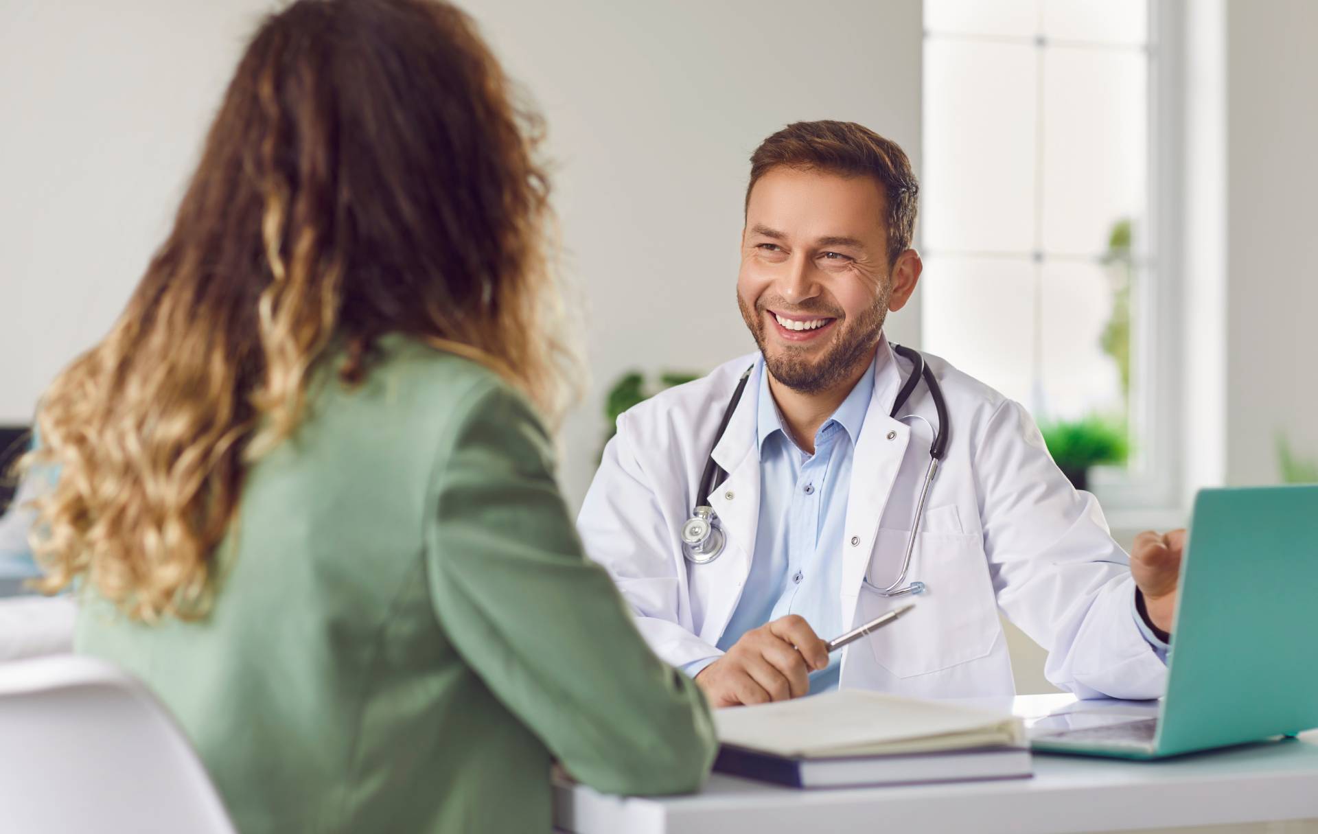 Doctor smiling while consulting with a patient at his desk.