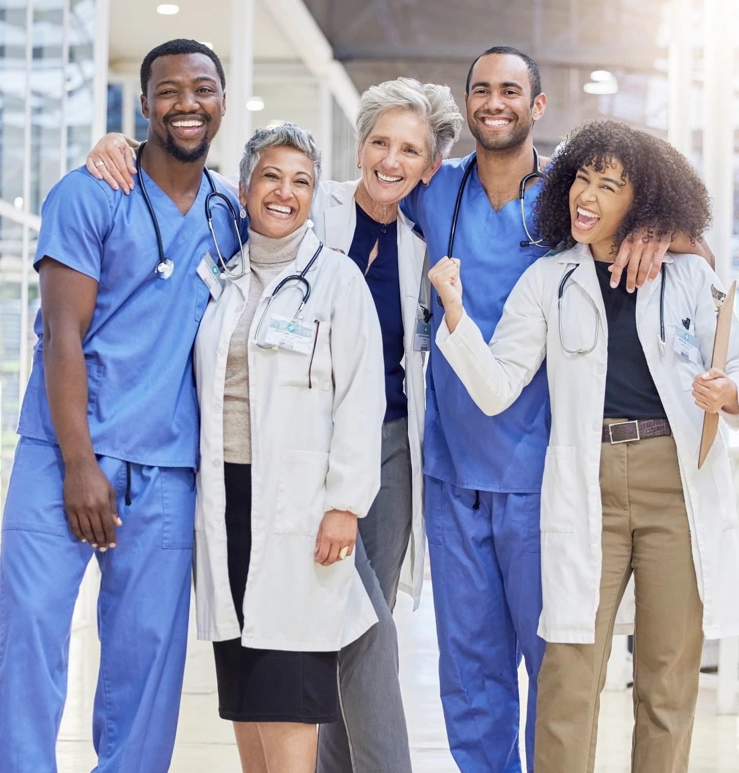 Diverse team of smiling doctors and nurses in a hospital hallway.