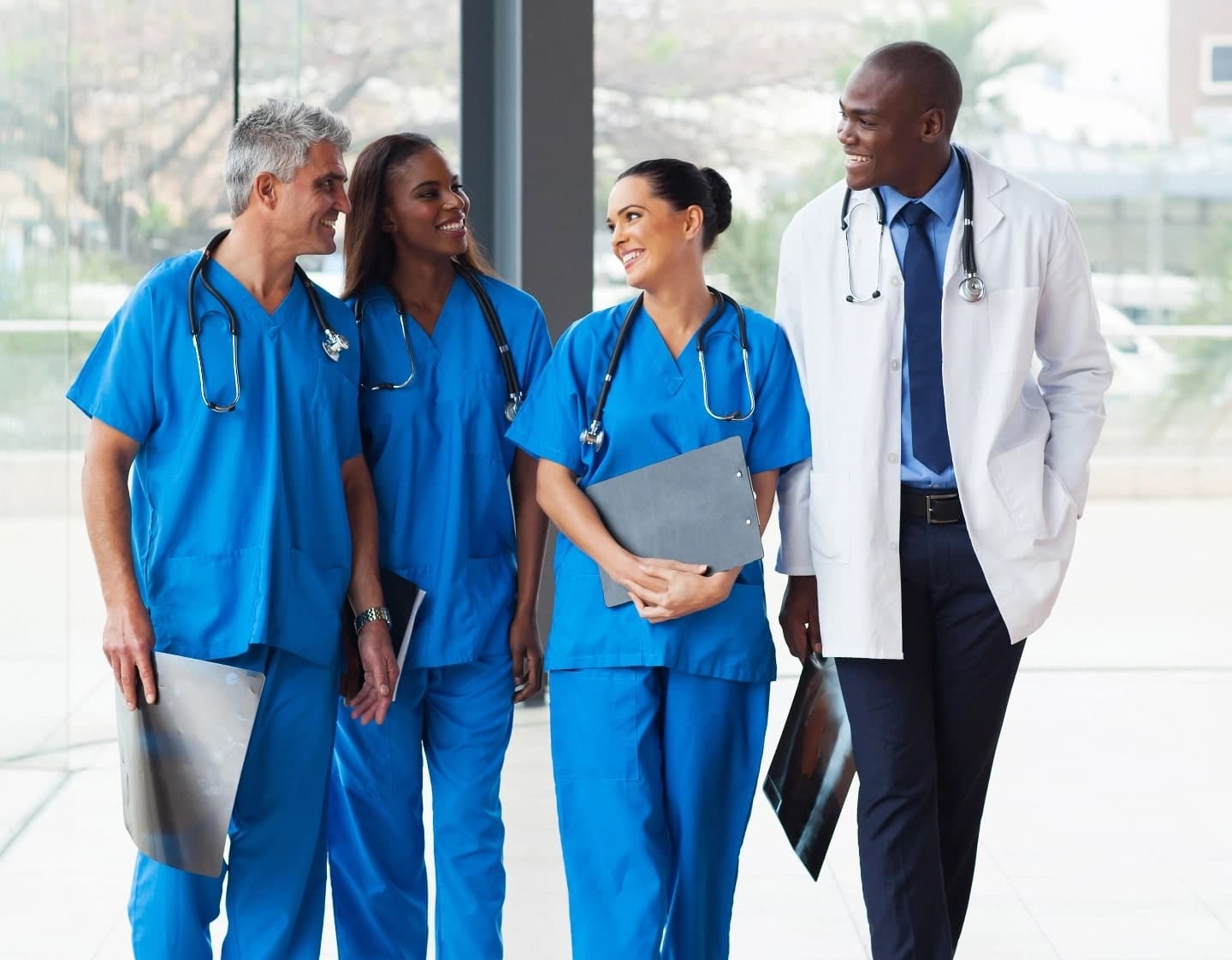 Diverse medical team: doctor and nurses in scrubs, smiling and walking with x-rays and charts.