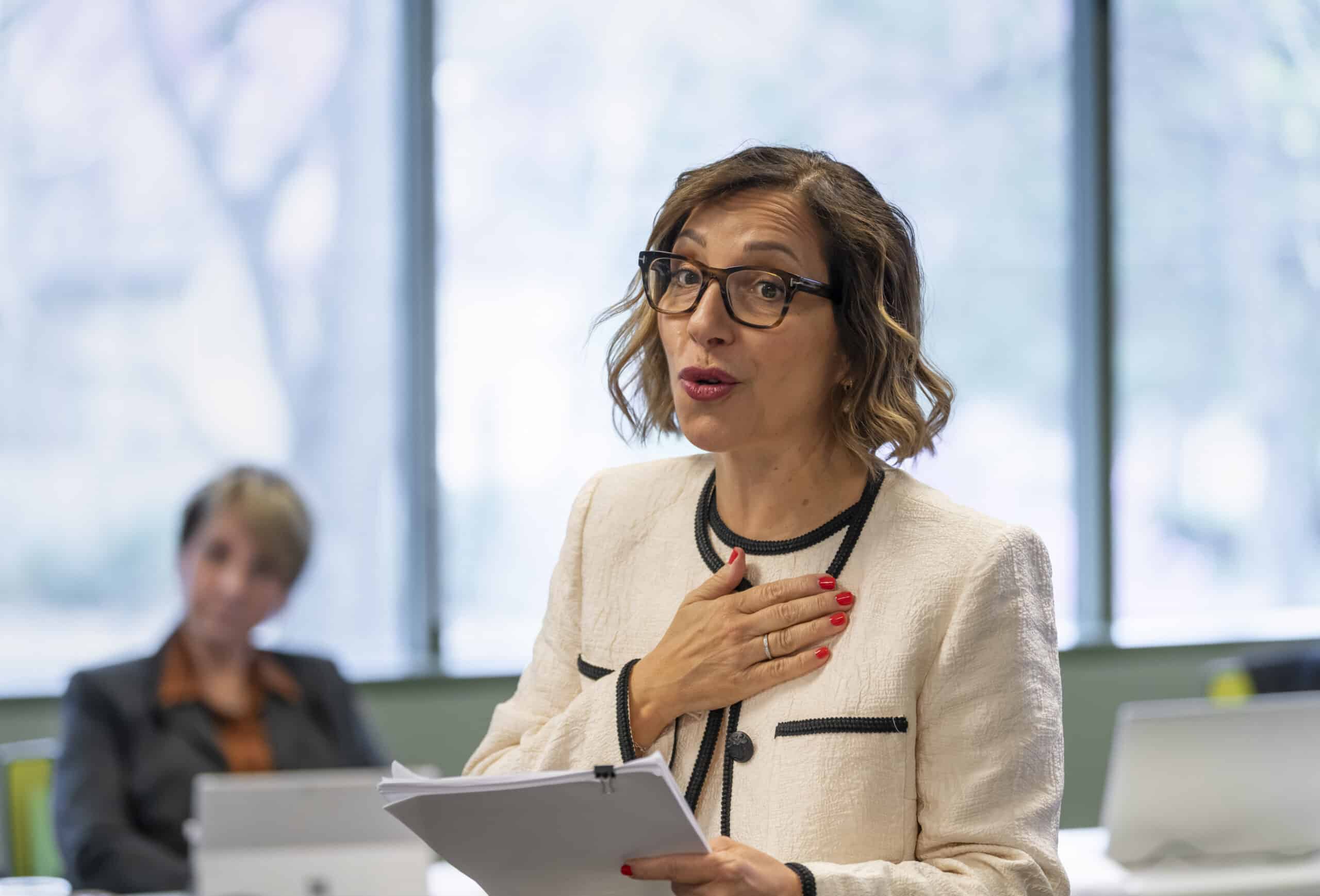Woman giving a keynote speech, holding papers.