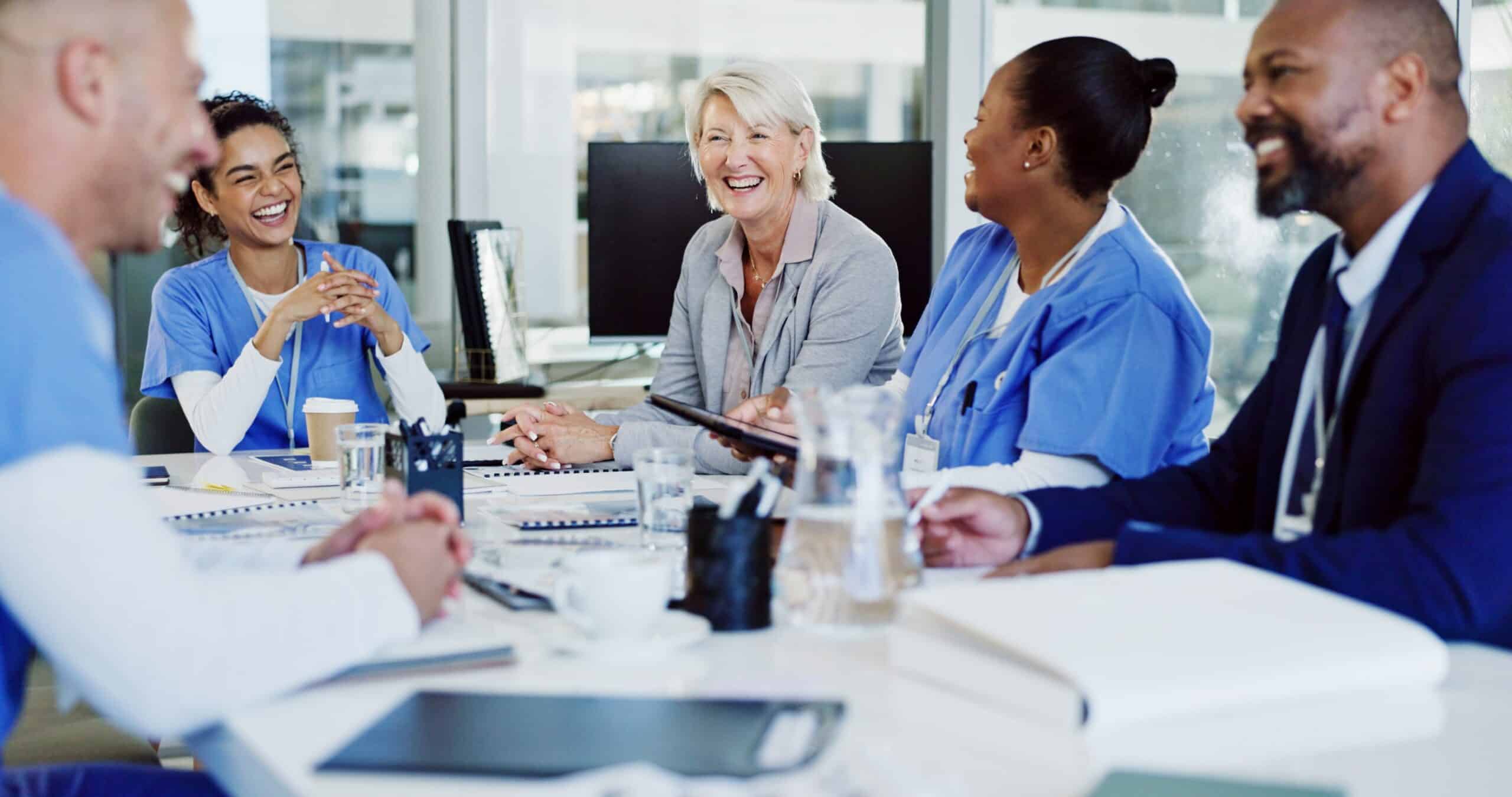Diverse healthcare team in a group coaching session, smiling and engaged.